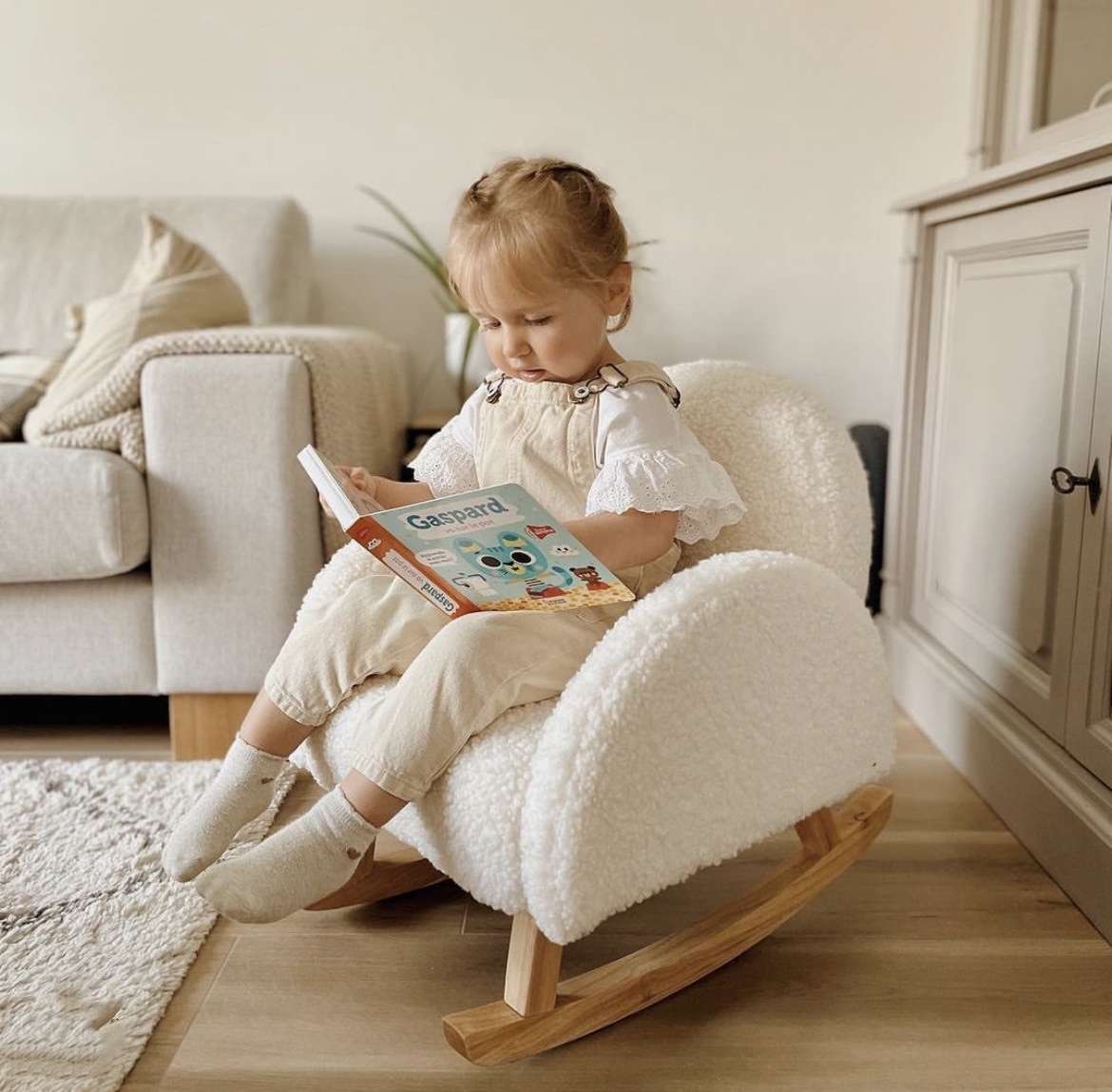 Enfant qui lit un livre sur le fauteuil à bascule teddy blanc par Childhome