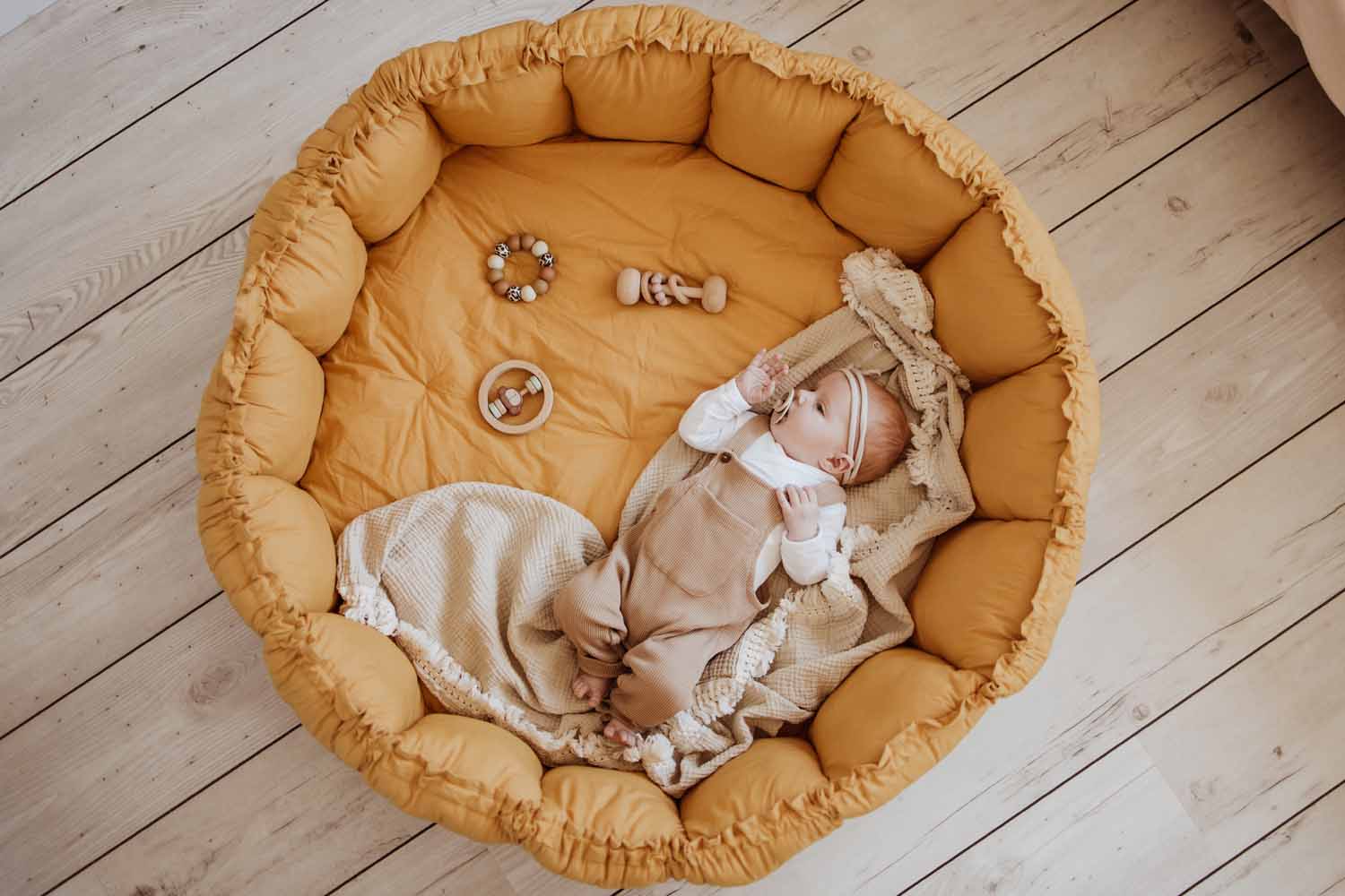 Bébé qui dort dans le tapis d'éveil Bloom moutarde aux bords relevés